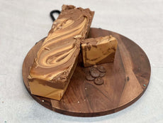 Creamy chocolate cheesecake fudge on a wooden platter with swirled top, enticing indulgence for your sweet cravings.