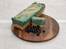 Blueberry cheesecake fudge on a wooden board with fresh blueberries, showcasing a delicious dessert option.